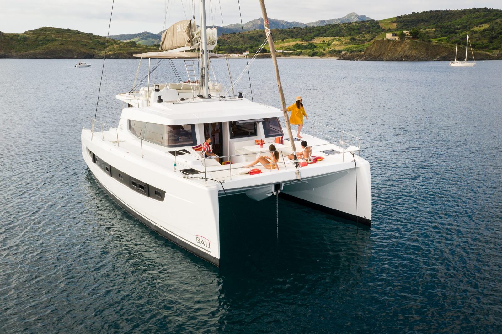 The BALI 4.8 catamaran anchored in a bay, guests on the foredeck