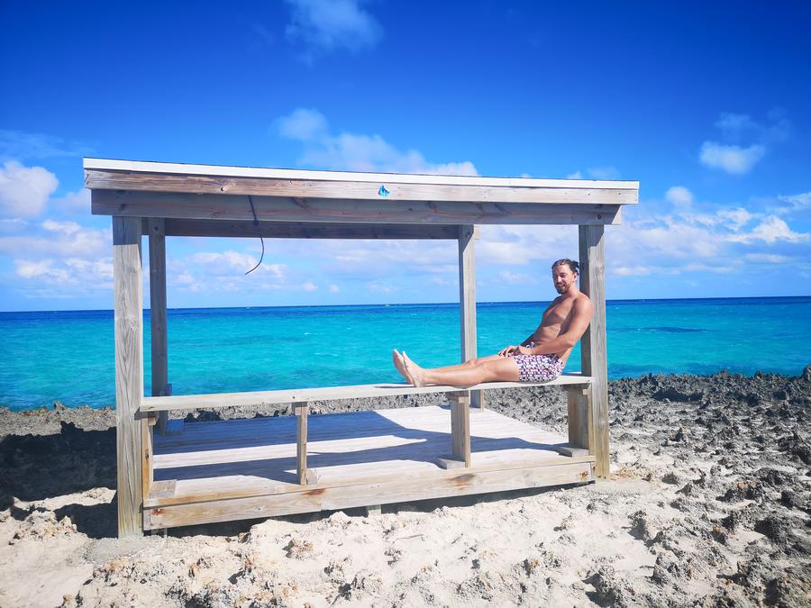 Relaxing in a wooden beach shelter above turquoise water