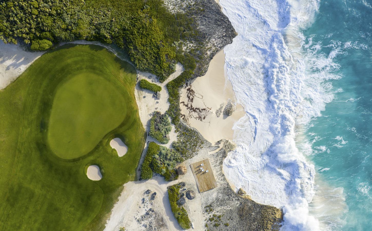 An ocean-front green, a hole surrounded by bunkers and the waves at The Abaco Club